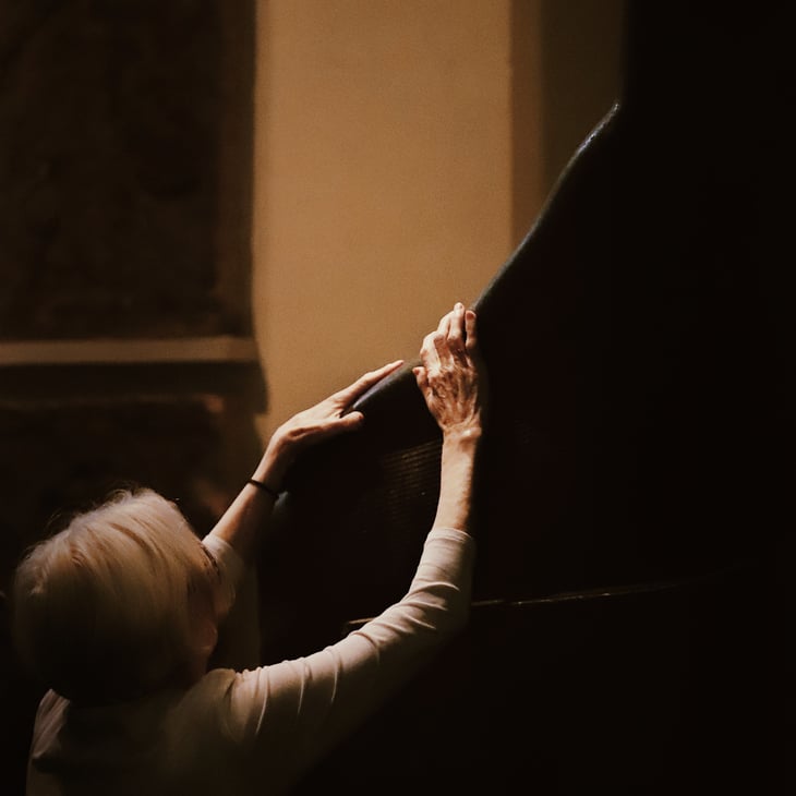 A pair of hands, delicate and expressive, reach out from the darkness to touch the face of an ancient Egyptian sculpture. The blind woman engages in a rare moment of multisensory access during a touch tour at the British Museum. All else in the photograph is shadowed, drawing attention to her hands as tools of perception, memory, and connection.