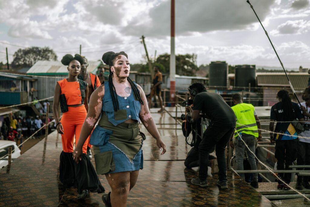 Julie strides down the runway wearing outfits by Hellen wanjiru Njengam, Designer of ‘Pocket Pennie’s swerve’ during Kibera Fashion Week, her gaze steady, her presence commanding.