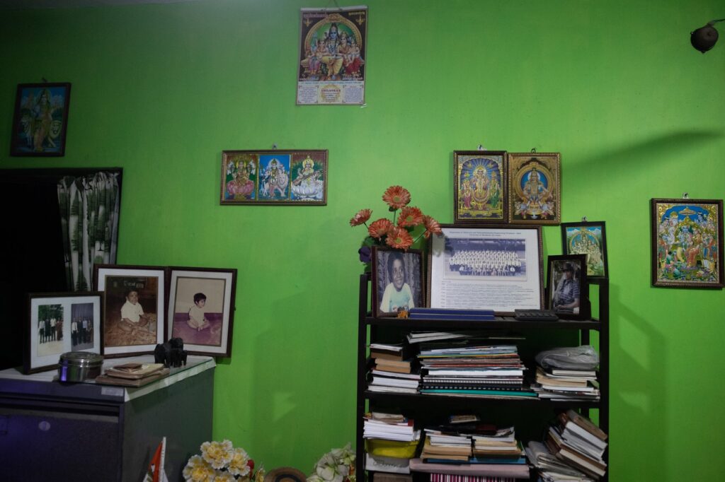 Photographs of the photographer's childhood, Hindu and Buddhist flags, and a hosts of memories and momentos clutter the bright green wall.