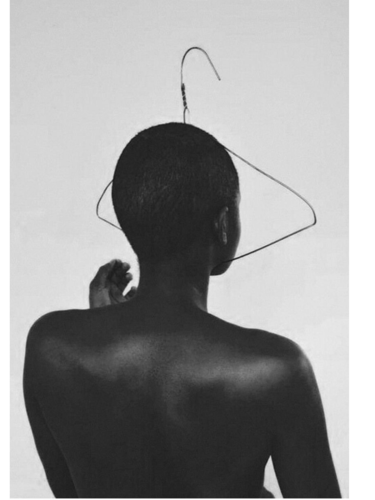 A figure stands naked, body turned away from the camera, a hanger stretched tightly over her face. Printed in archival black and white on Hahnemühle Etching paper, the work confronts abortion laws and the contested terrain of bodily autonomy.